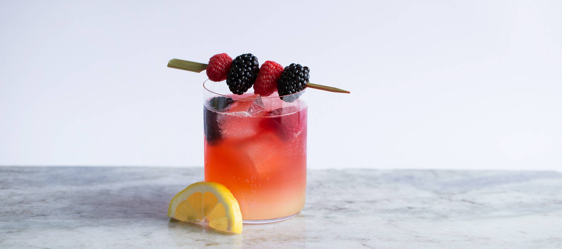 tequila sunrise cocktail with fresh berries and lemon